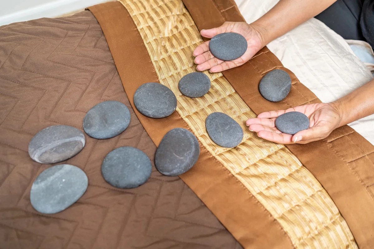 Warm basalt stones laid out in rows on a towel next to the massage table