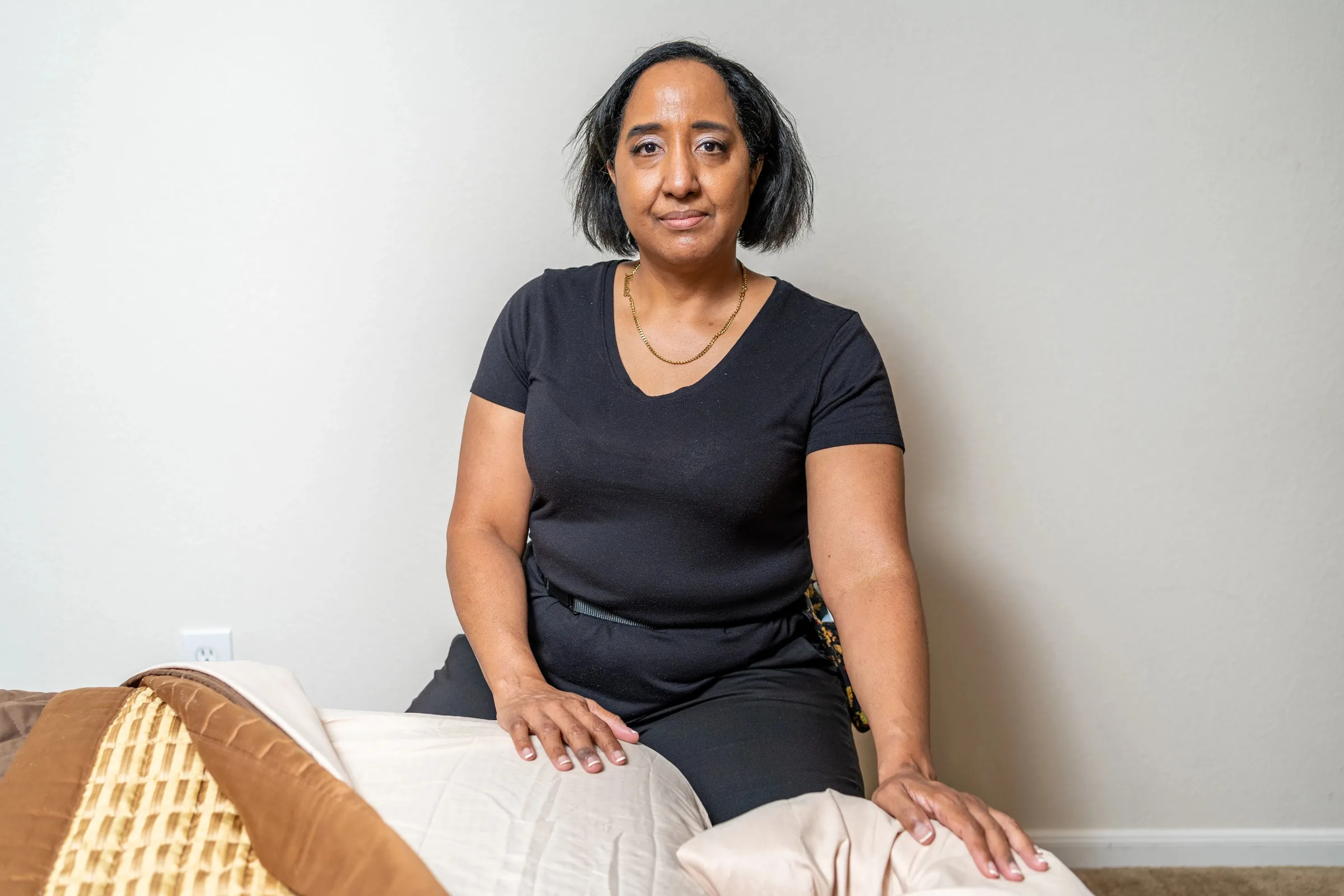 Nina Taylor seated beside her made-up portable massage table in a client's home